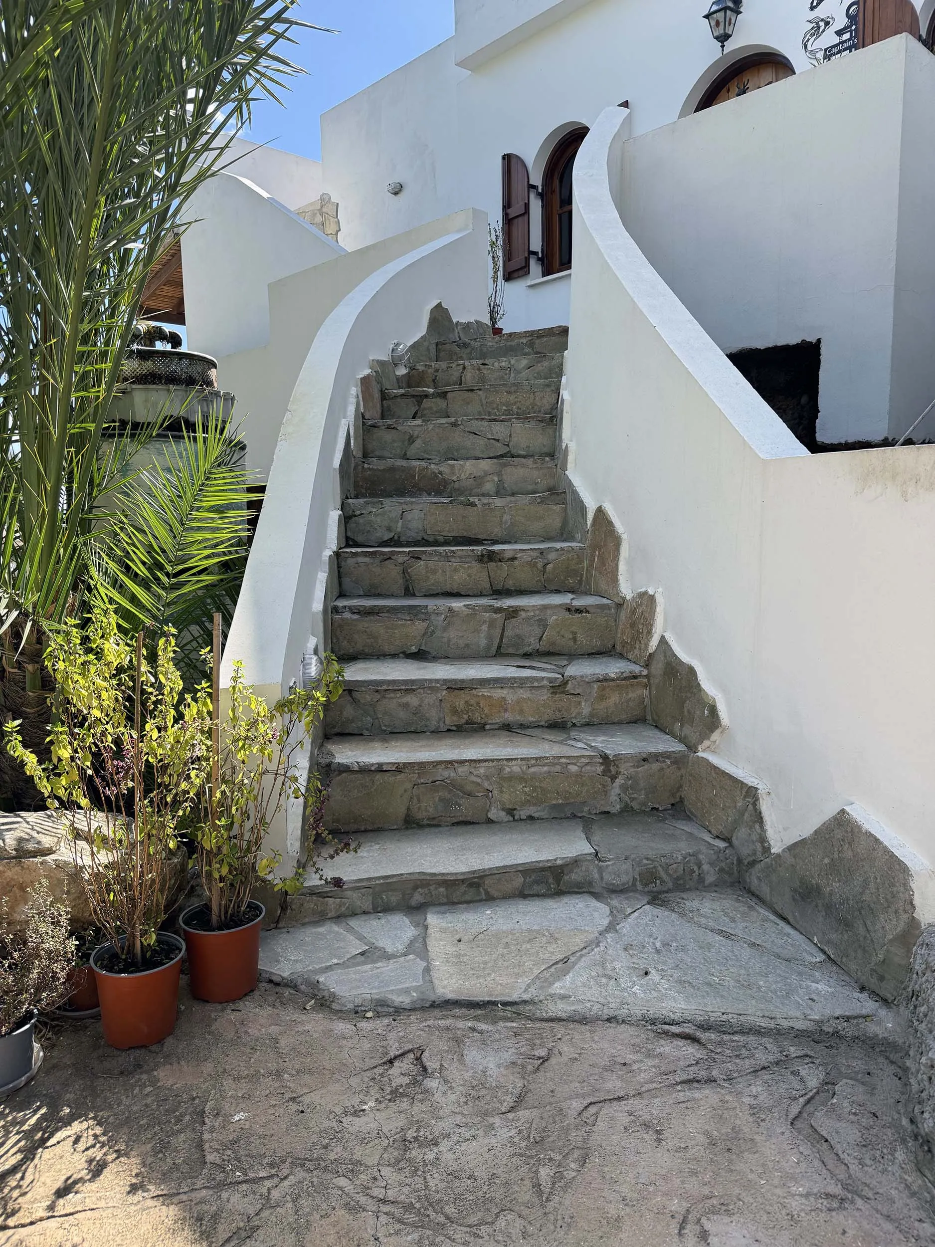 Stone staircase with white rendered walls and potted plants at the cottage entrance
